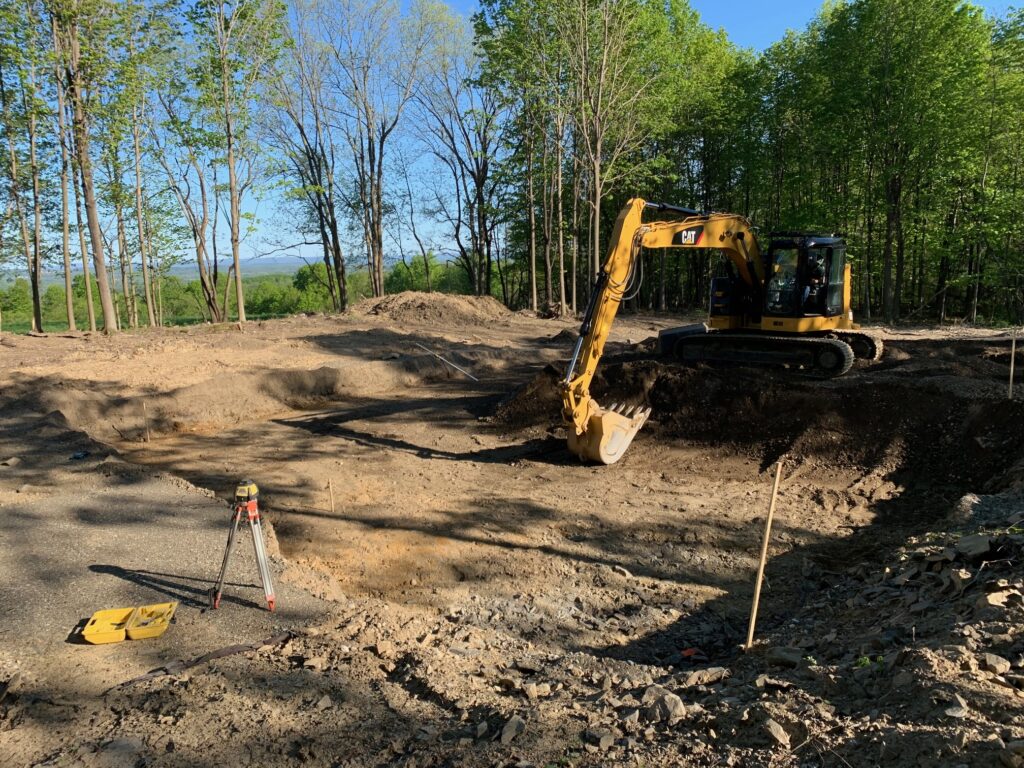 A bulldozer at a construction site, positioned next to a tree.